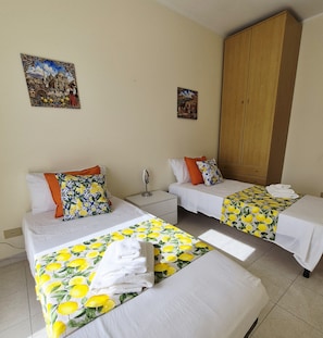 A hotel room with two beds, a wardrobe, a nightstand with a mirror, and two wall-mounted pictures. - 100 m² apt with free parking over the citrus garden– for families in Trappitello (Trappitello)