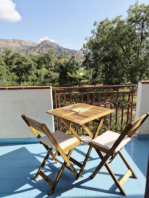 A wooden table and two chairs on a balcony with a view of a mountainous landscape. - 100 m² apt with free parking over the citrus garden– for families in Trappitello (Trappitello)
