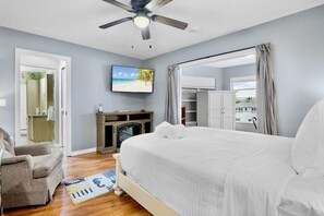 A bedroom with a bed, a chair, a television, a fireplace, and a wardrobe. - Island Bay House A in Anna Maria Island (Holmes Beach)