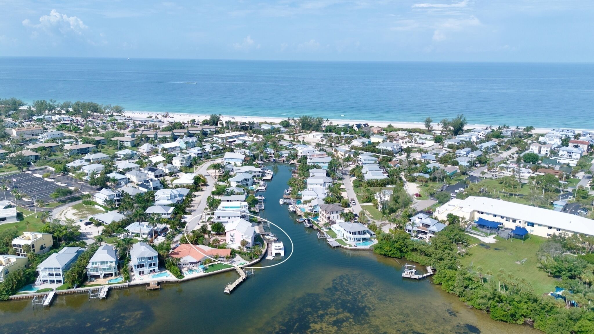 Une zone résidentielle côtière comprenant des maisons, un port de plaisance et une plage.