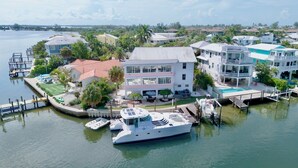 A waterfront property with a large house, a dock, and a yacht. - Island Bay House B in Anna Maria Island (Holmes Beach)
