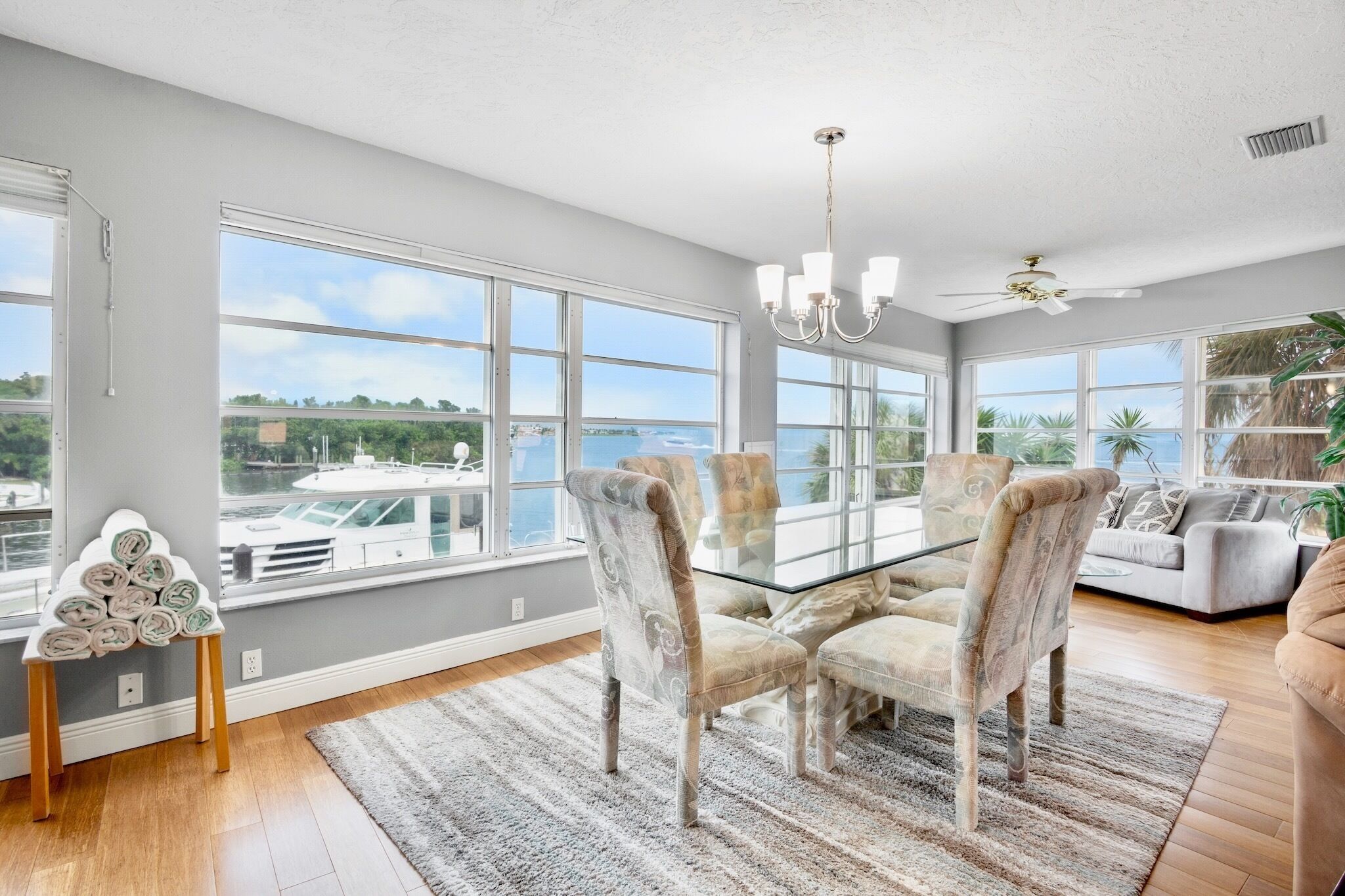 A spacious room with large windows, a dining table, and a sofa.