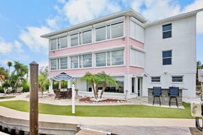 Un bâtiment à deux étages doté d’un patio aménagé avec des meubles d’extérieur et des palmiers.