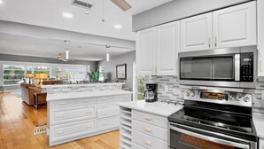A modern kitchen with white cabinetry, a built-in microwave, and a stove. - Island Bay House B in Anna Maria Island (Holmes Beach)