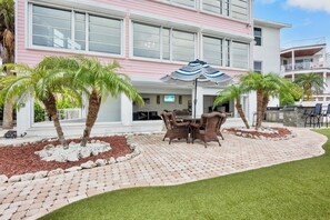 Ein Hotel mit einer Terrassenanlage, die Gartenmöbel und Palmen beherbergt.