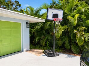 A residential garage with a basketball hoop, a green door, and a white garage door. - Private heated pool & hot tub near AMI and IMG (Bradenton)