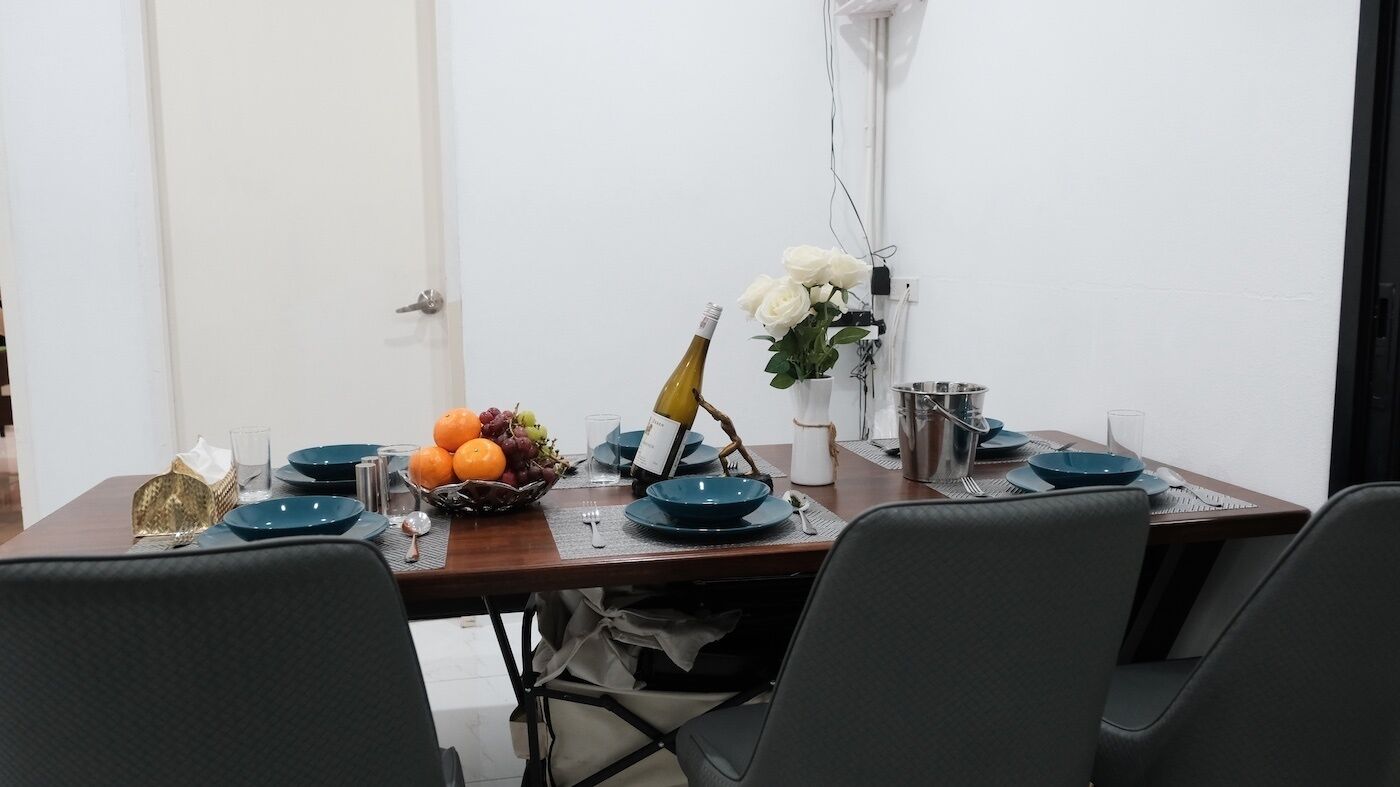 A dining table set with blue plates, a bottle of wine, and a fruit basket.
