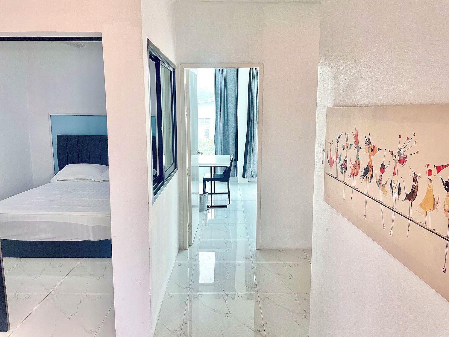 A hotel room with a bed, a desk, and a painting on the wall.
