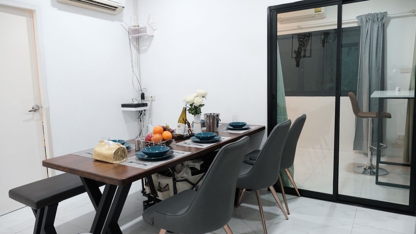 A dining area with a table set for four, a bench, and a view through a glass door.