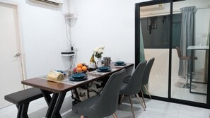 A dining area with a table set for four, a bench, and a view through a glass door.