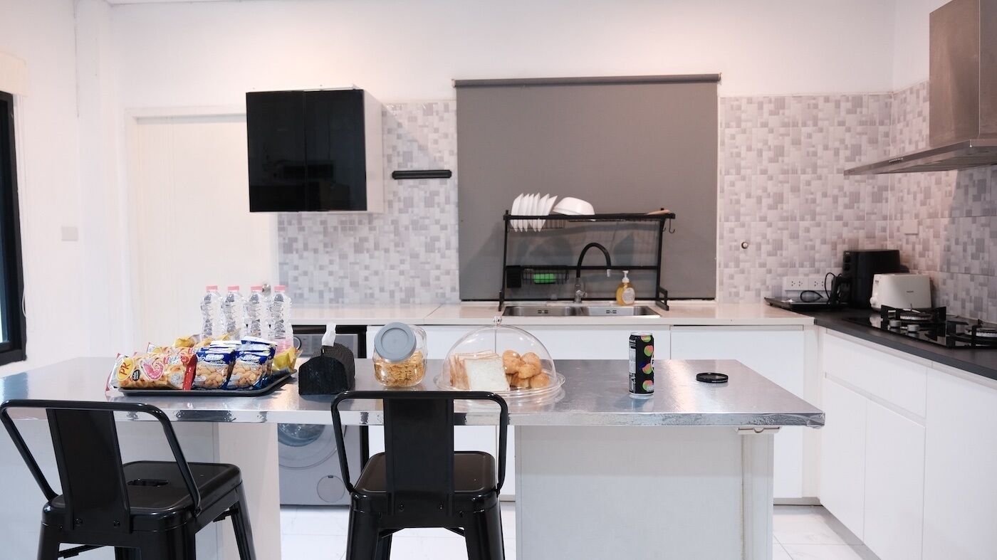 Une cuisine moderne avec un îlot central, des chaises noires et une variété d’aliments.