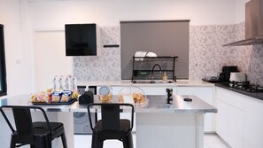 Una cocina moderna con una isla central, sillas negras y diversos alimentos.