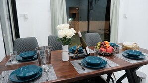 Une table à manger dressée avec de l’argenterie, des assiettes bleues et un vase rempli de fleurs blanches.