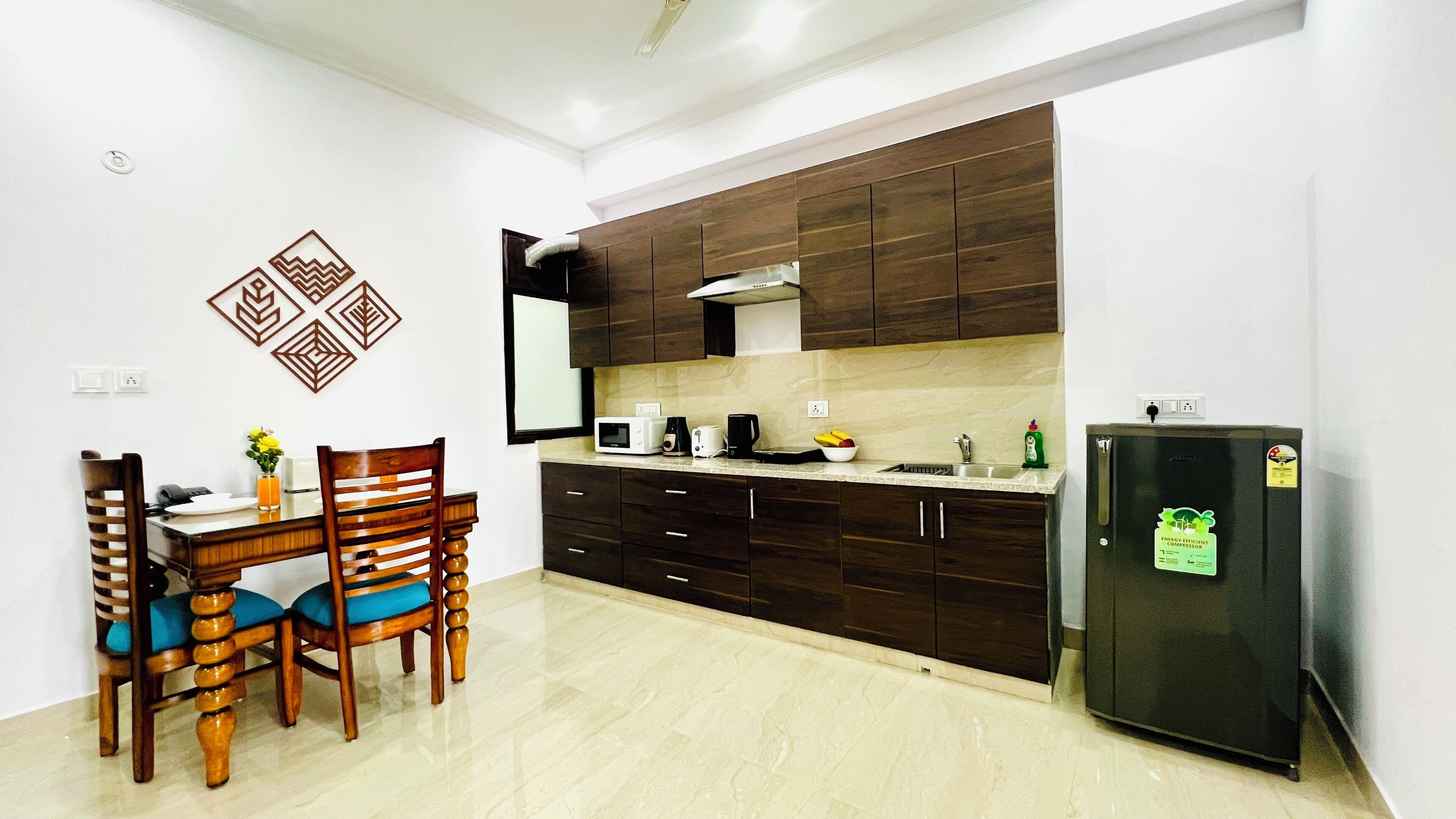 A modern kitchen with dark wooden cabinets, a built-in microwave, and a refrigerator.