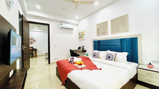 Una habitación de hotel moderna con una cama grande, un escritorio, una silla y una televisión.
