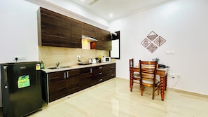 A modern kitchen with dark wood cabinets, a built-in microwave, and a dining area with a wooden table and chairs.