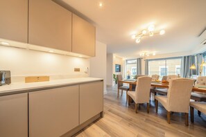 A modern kitchen with a dining area, wooden flooring, and pendant lighting. - Modern & Sleek 3BR, 2.5BA, Lift, AC, Centeral London (London)