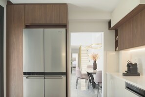 A modern kitchen with a built-in stainless steel refrigerator, wooden cabinetry, and a dining area with a table and chairs. - Vitsila Villa II, Design, Sea Views & Family Fun (Rethymno)