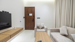 Una sala de estar moderna con un televisor de pantalla plana, una mesa de centro de madera, un sofá gris y un sofá color beige.