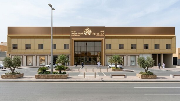 Un hotel moderno con entrada central, varios pisos y un área frontal ajardinada con macetas.