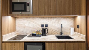 A modern kitchen with wooden cabinets, a built-in microwave, a coffee maker, and a dishwasher.