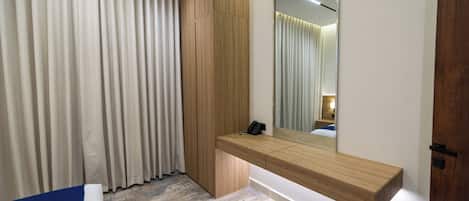 A modern bedroom with a built-in wooden bedside table, a large mirror, and a bed with a blue accent.