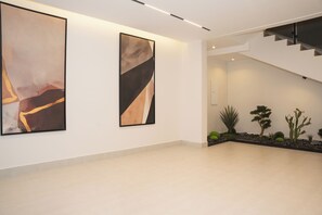 A modern interior with two large abstract paintings on the wall, a staircase, and a small indoor garden with cacti. - Arjan Park Tuwaiq 3 (Riyadh)