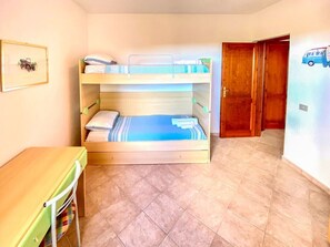 Ein Zimmer mit einem Etagenbett, einem kleinen Tisch und einer Tür zu einem anderen Raum.