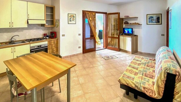 A compact living space with a kitchenette, a dining area, a sofa, and a television. - Green Garden House - Relaxation and a Private Garden in Malamurì (Malamurì)