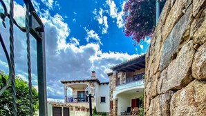 A stone pathway leading to a building with a balcony and a stone wall. - Green Garden House - Relaxation and a Private Garden in Malamurì (Malamurì)