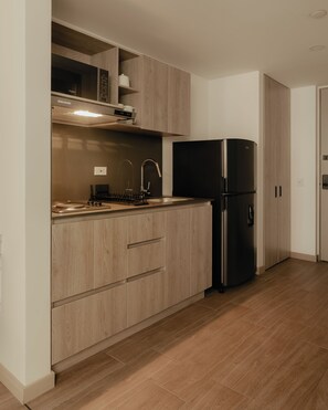 Eine moderne Küche mit Holzausstattung, einem Edelstahl-Kühlschrank und einer eingebauten Mikrowelle.