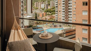 A balcony with a hanging chair, a small table with a cup and saucer, and a book. - Studio Nomad Pro | A/C, just steps from the Metro (Sabaneta)