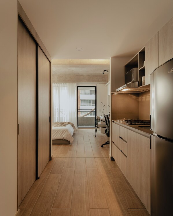 Eine moderne Küche mit Einbaukühlschrank, ein Essbereich mit einem Stuhl und ein Schlafzimmer mit einem Bett.