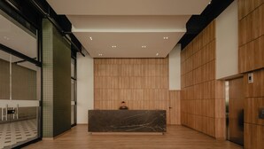 A modern reception area with a marble reception desk, wooden panel walls, and a glass partition on the left. - Studio Nomad Pro | A/C, just steps from the Metro (Sabaneta)