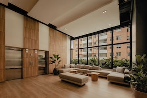 Ein modernes Interieur mit Holzboden, einer Sofagarnitur, einem Couchtisch und einem großen Fenster mit Blick auf ein Ziegelgebäude.