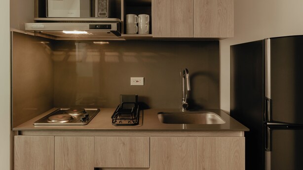 A modern kitchen with a built-in microwave, a stainless steel sink, and a black refrigerator. - Studio Nomad Pro | A/C, just steps from the Metro (Sabaneta)