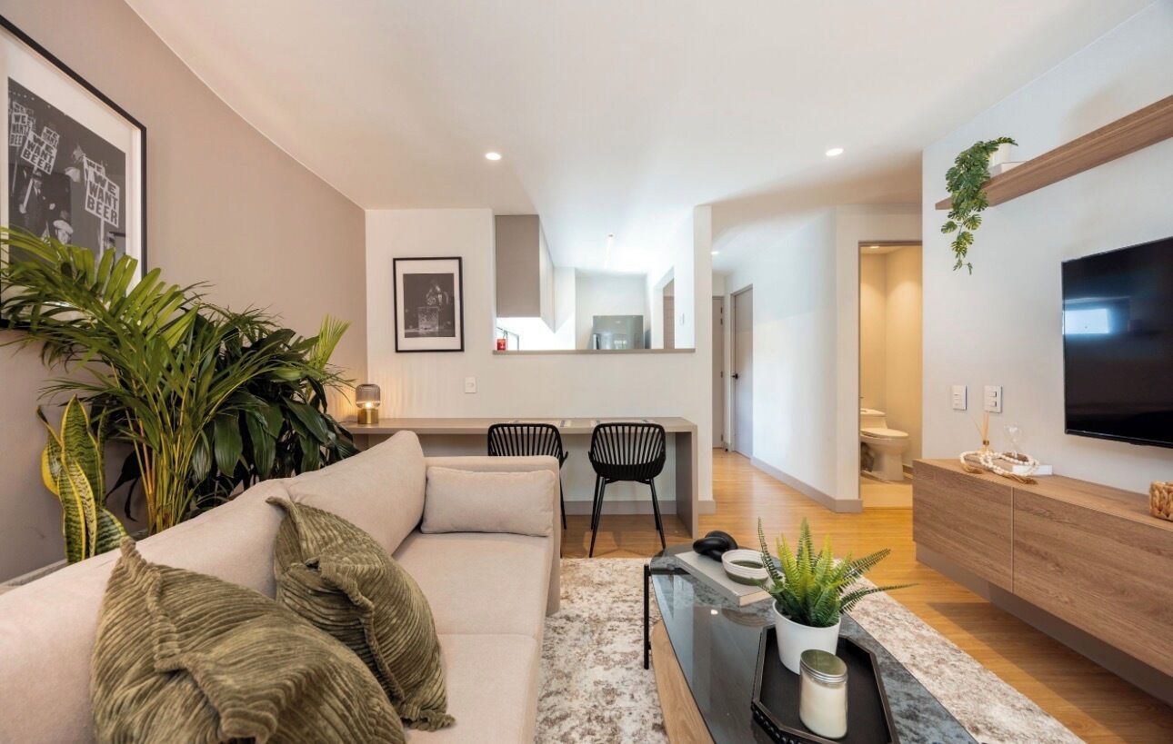 A modern living room with a sofa, coffee table, and a TV mounted on the wall.