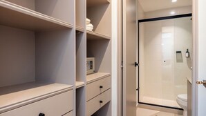 A bathroom with a shower, toilet, and storage cabinets. - Live in Provenza Modern 1 BR Security (Medellín)