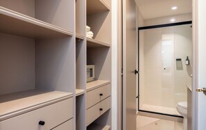 A bathroom with a shower, toilet, and storage cabinets. - Live in Provenza Modern 1 BR Security (Medellín)