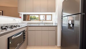 A modern kitchen with a built-in oven, a stainless steel refrigerator, and a window above the sink. - Live in Provenza Modern 1 BR Security (Medellín)