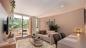 A modern living room with a sofa, coffee table, and dining area. - Live in Provenza Modern 1 BR Security (Medellín)