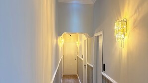 A hallway with a wooden floor, white walls, and a ceiling with a skylight.