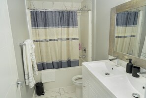 A bathroom with a shower curtain, a toilet, a sink with a mirror, and a towel rack. - Quiet neighbourhoo
Family friendly
Edmonton Expo Centre
Convenient & comfortable (Edmonton)