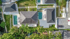 Vista aérea de um bairro residencial com várias casas, uma piscina e um jardim bem cuidado.
