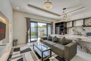 A modern living room with a sofa, coffee table, and a TV screen. - Shala Suites Bali - Pererenan (Mengwi)