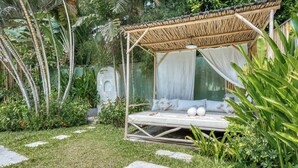 Uma cama com dossel em um jardim exuberante.