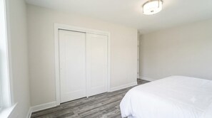Un dormitorio con cama, armario e iluminación en el techo.