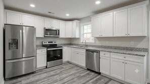 Una cocina moderna con armarios blancos, electrodomésticos de acero inoxidable y encimera de granito.
