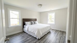 Un dormitorio con una cama, dos ventanas y una lámpara en el techo.