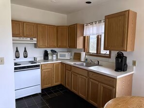 A kitchen with wooden cabinets, a white stove, a microwave, and a coffee maker. - Vacation Home. 4 Minutes to Hunter Mountain! (Hunter)
